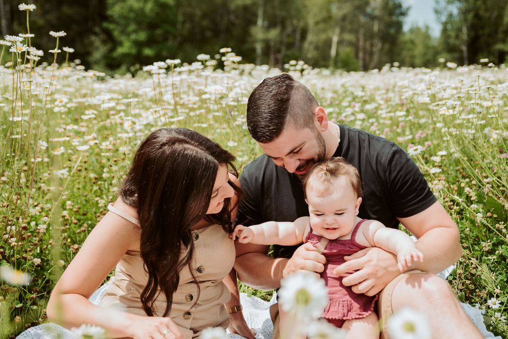 Happy family moment captured in a field of white daisies during summer.