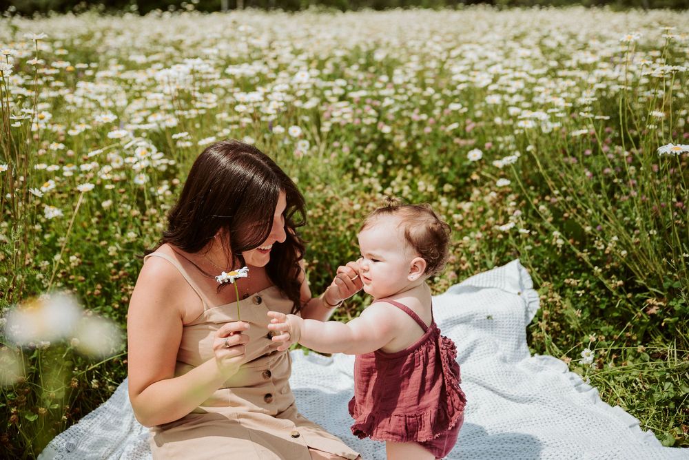 Tender family moment on a white blanket surrounded by wildflowers.