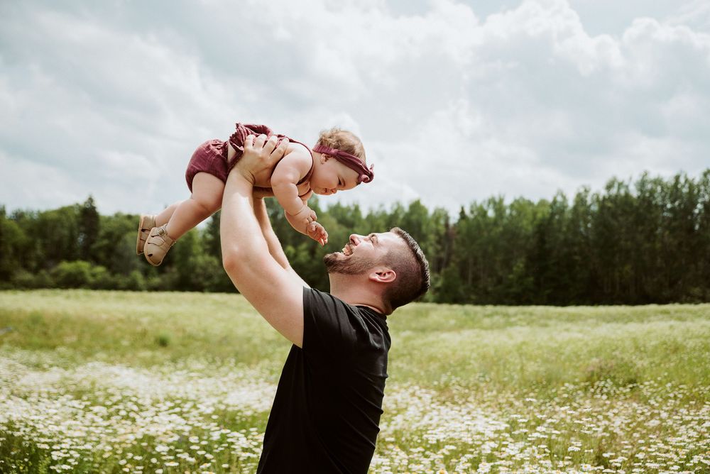 Playful family moment in a meadow filled with white wildflowers.