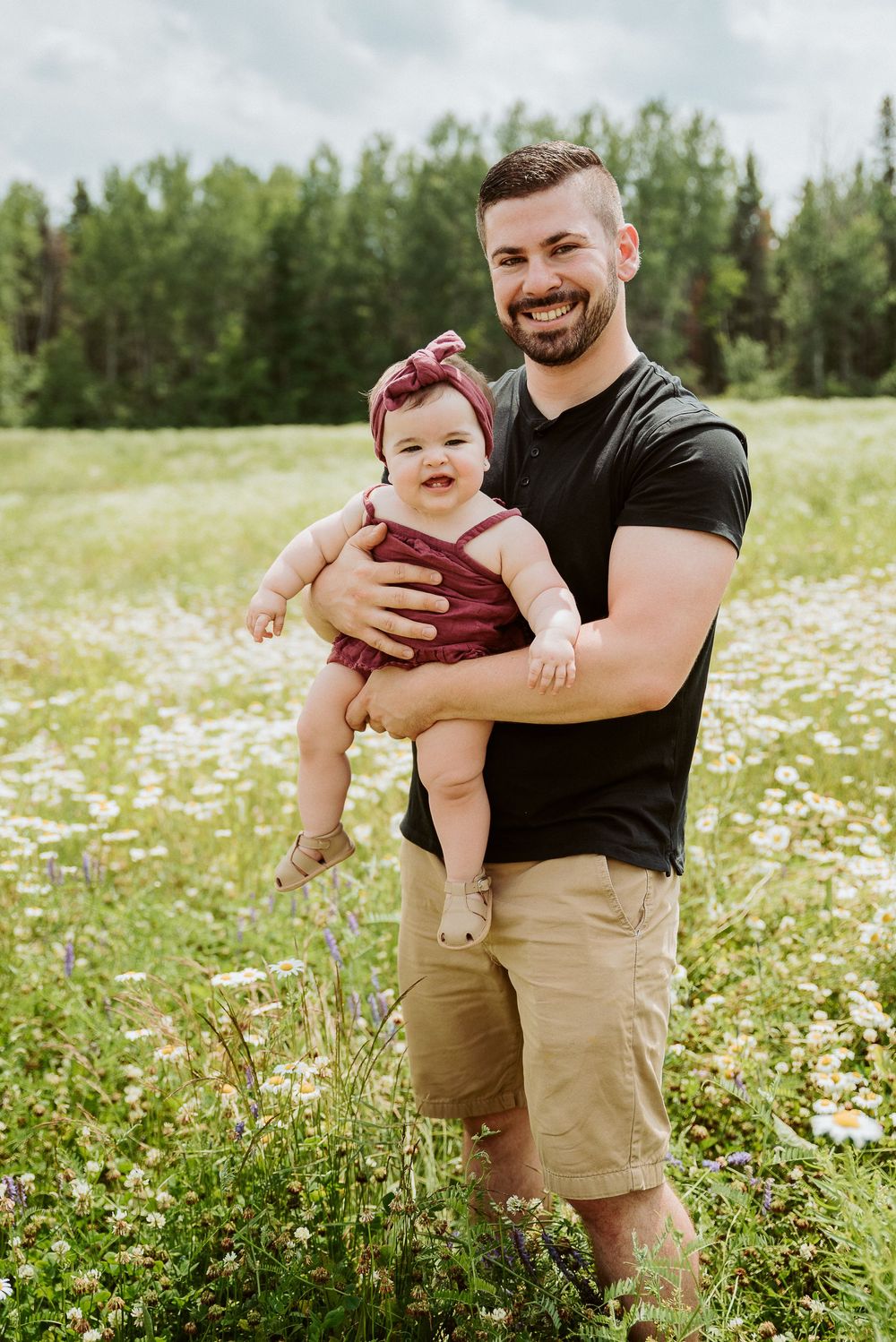 Joyful interaction between family members in a daisy-filled summer field.