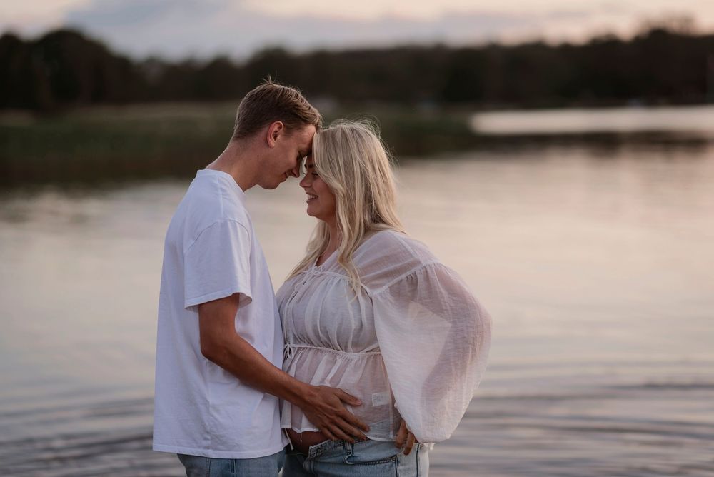 Intimate moment captured between two people on a waterfront during golden hour.