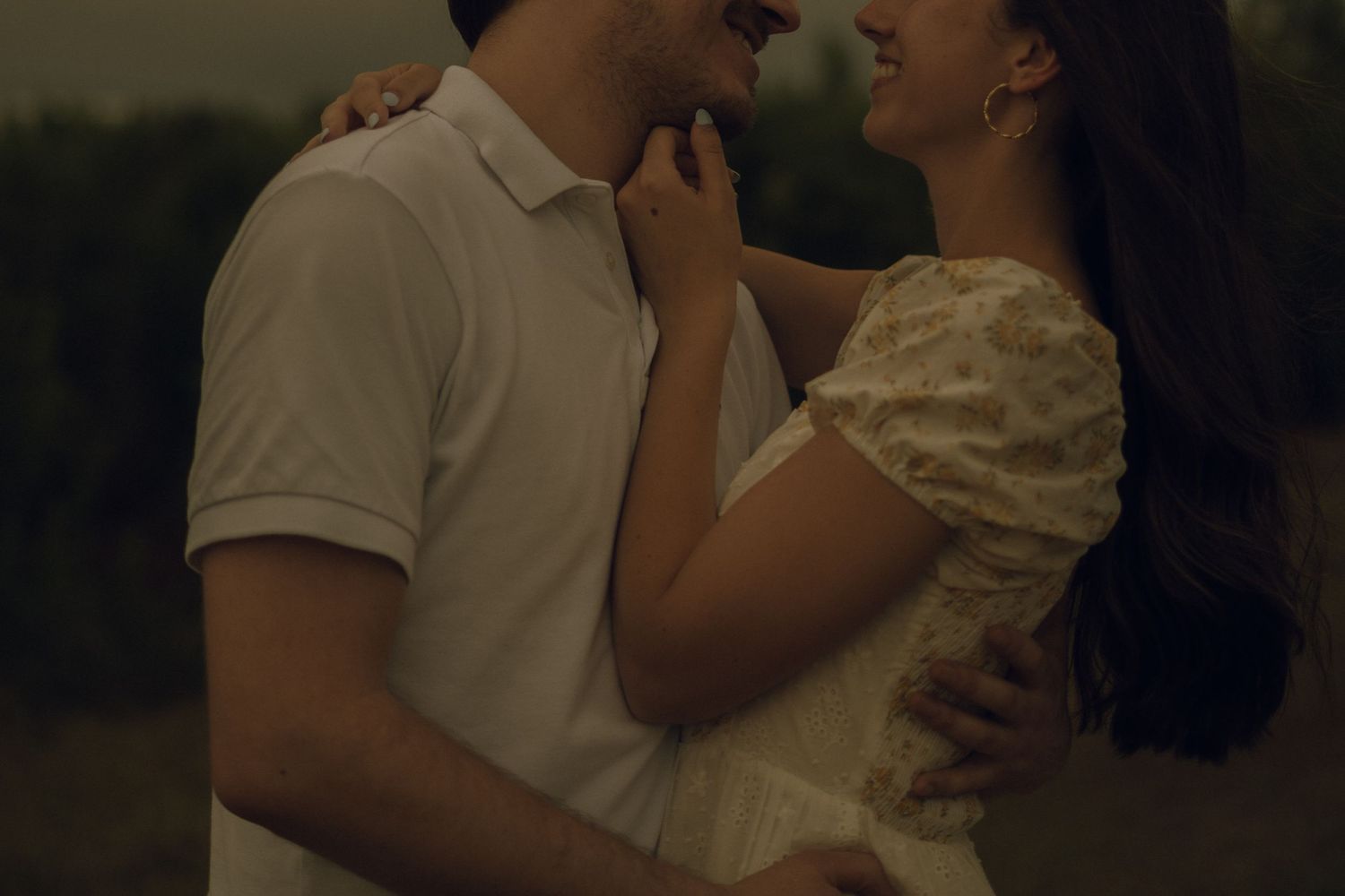 m/f couple in field hugging closely and smiling at each other