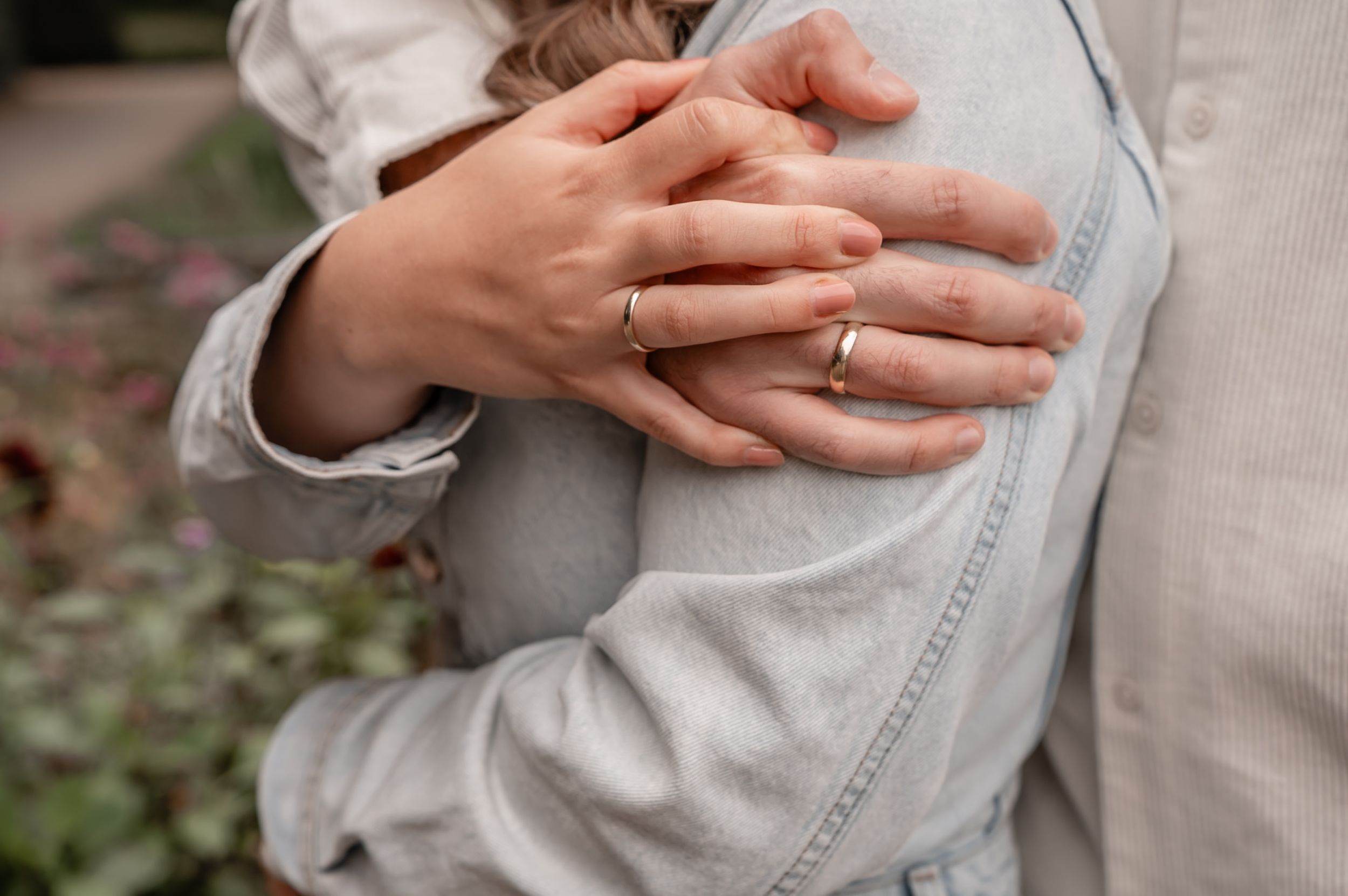 Close-up photo of hands holding a soft gray knit sweater against a blurred outdoor background.