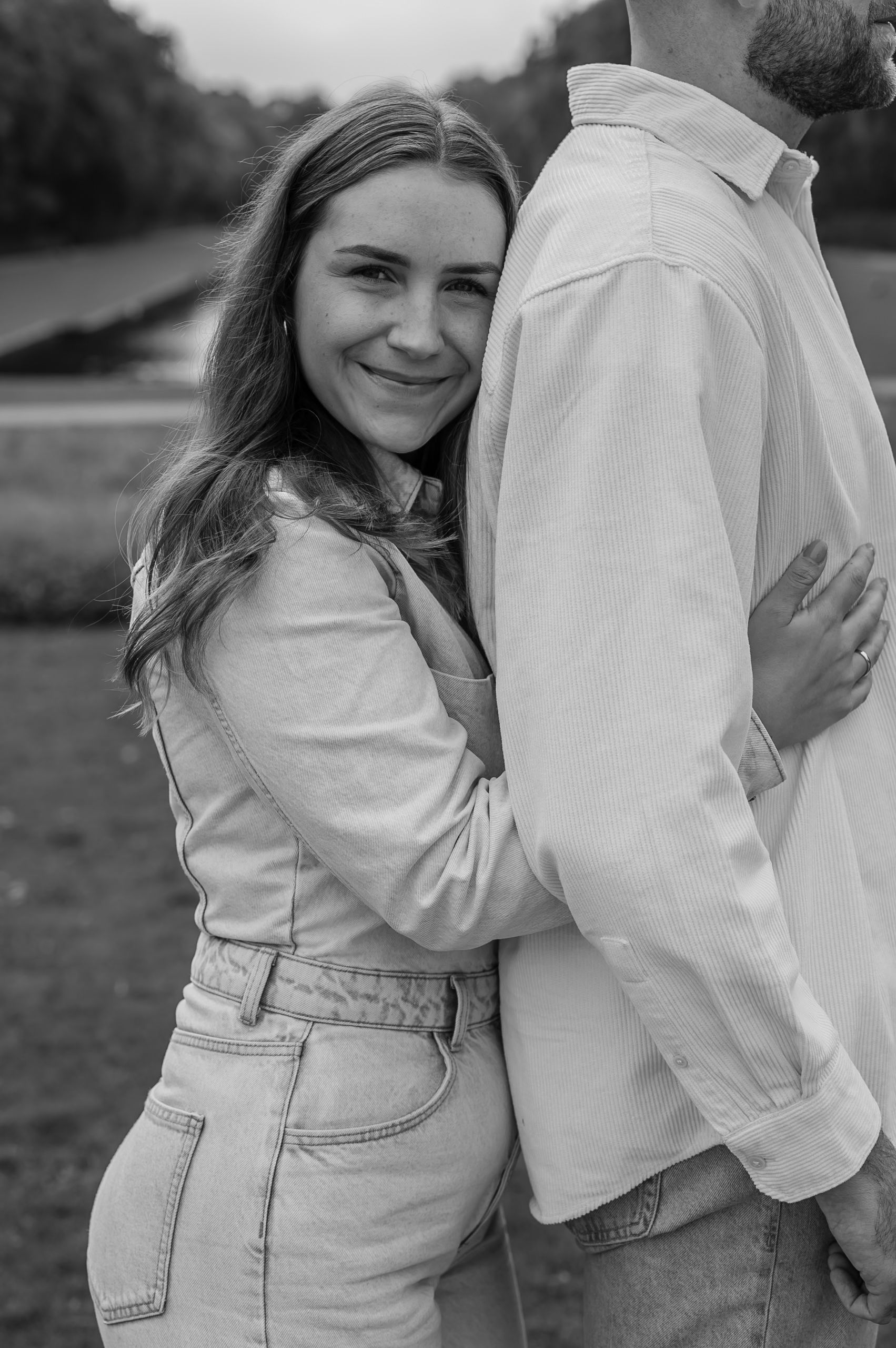 Black and white photo series showing a couple embracing in casual outfits with denim and white clothing outdoors.