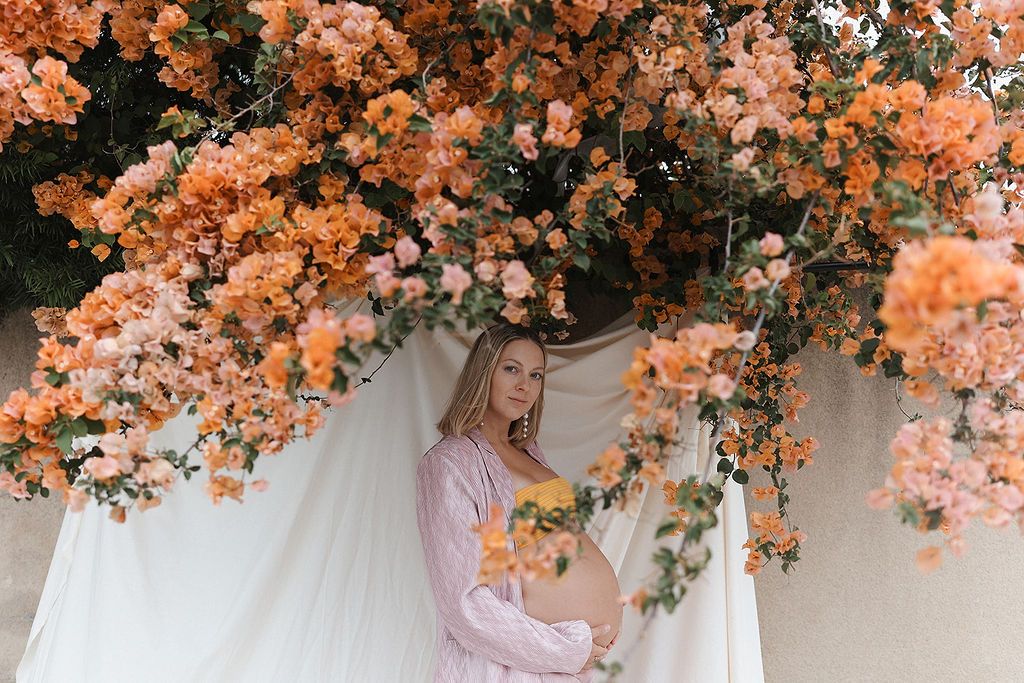 An ethereal wedding ceremony arch decorated with cascading peach and coral roses under soft natural lighting.
