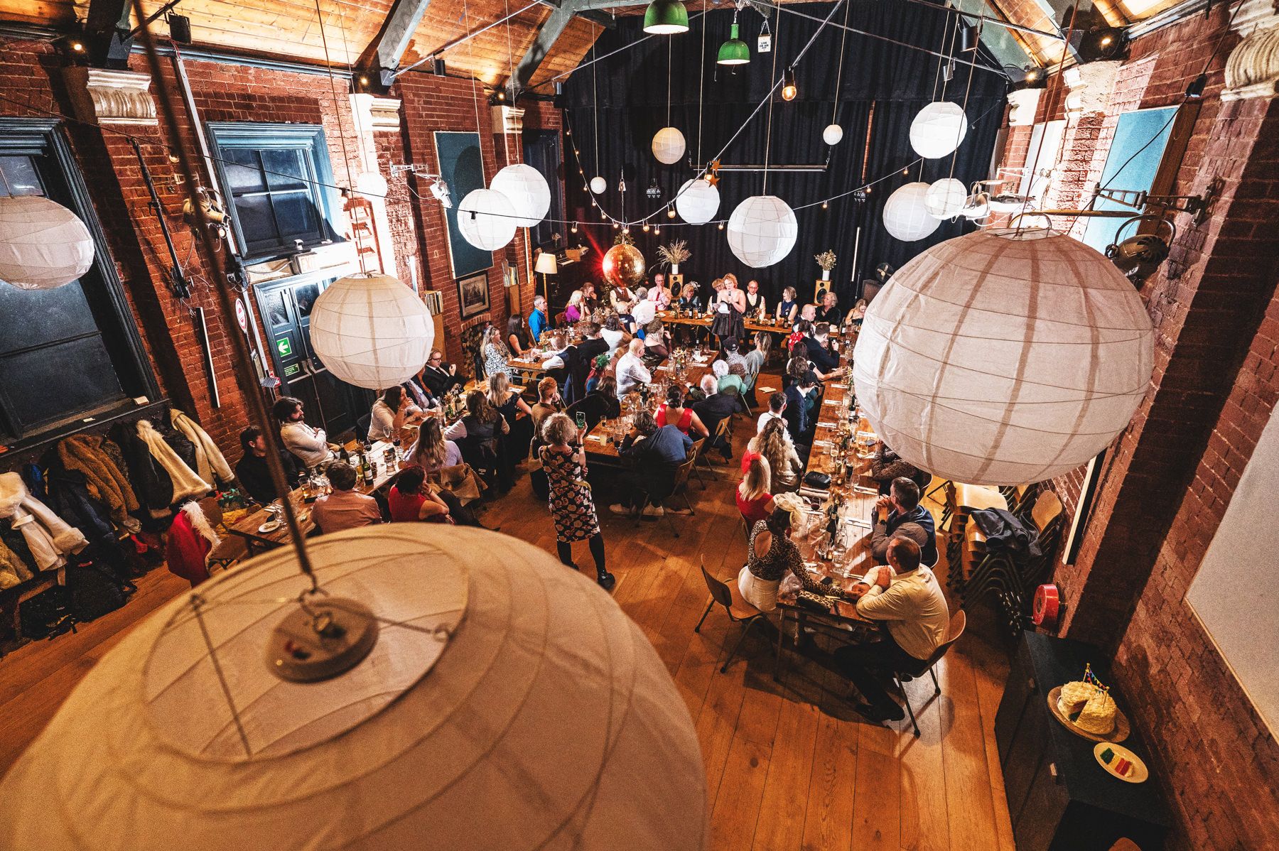 An overhead view of a lively wedding reception venue with paper lanterns and exposed brick decorated in rustic style.