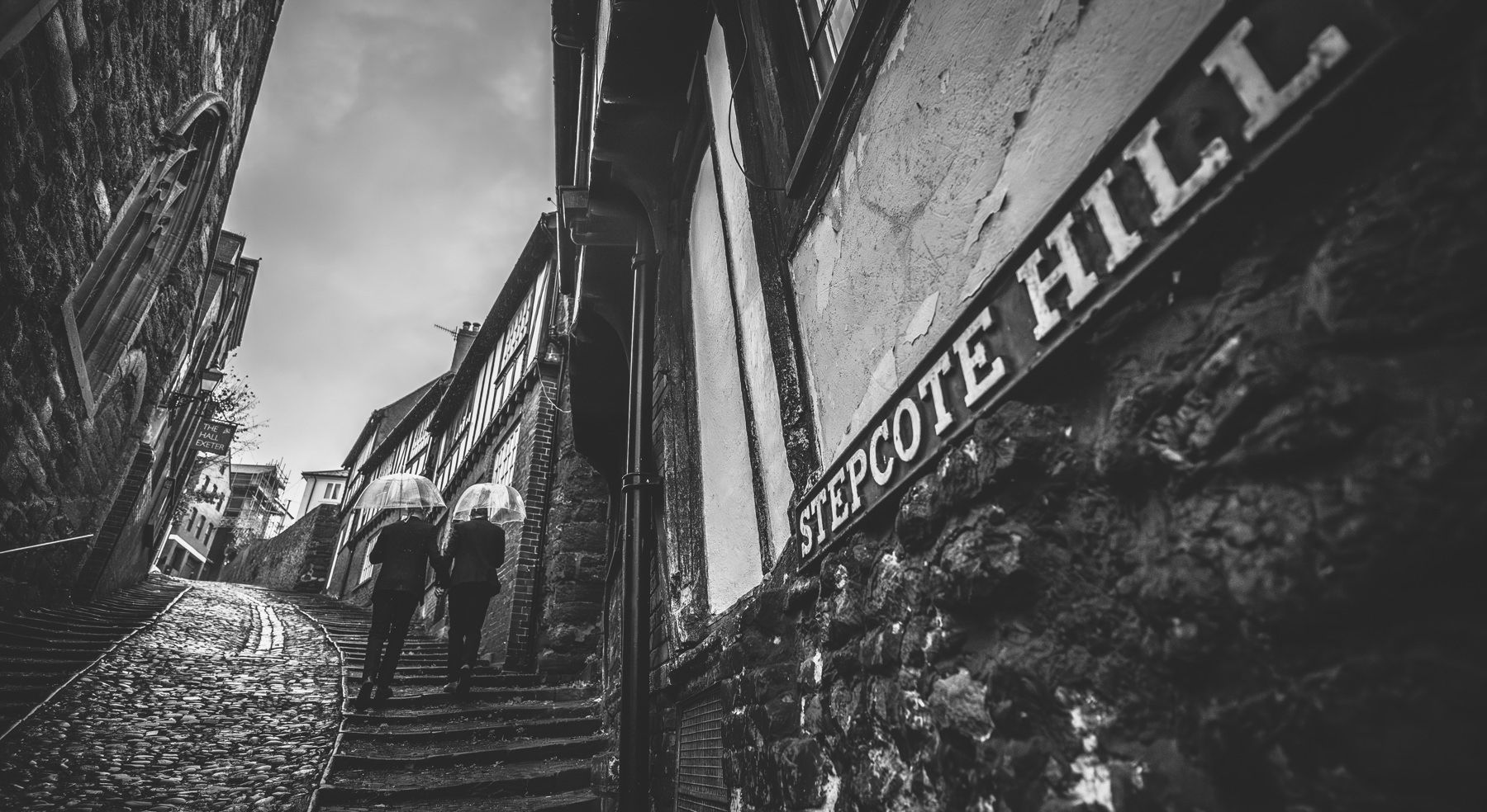 A steep cobblestone street in black and white leads up to Notting Hill in London with historic buildings along both sides.