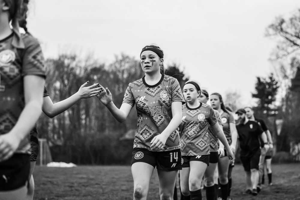 Football players in an outdoor field share laughter and smiles at practice in black and white.