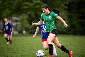 Two soccer players compete for the ball during an intense match on a grass field.