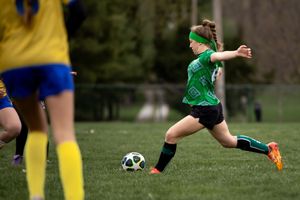 Close up of soccer players' feet battling for possession of the ball during a competitive match on grass field.