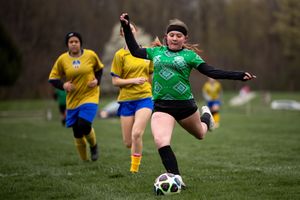 Soccer players compete for possession during an outdoor match with players wearing yellow and green jerseys.