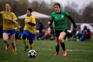 Soccer players compete for possession of the ball during an intense match on a grass field.