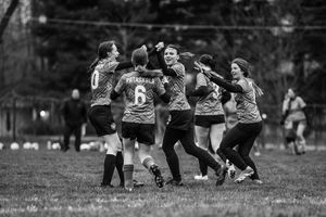 Rugby players engage in a team huddle formation on a grass field during a match or practice session.