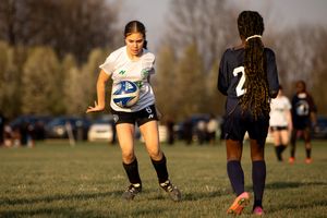 Athletes compete in a soccer match on a sunny grass field during an intense game sequence.