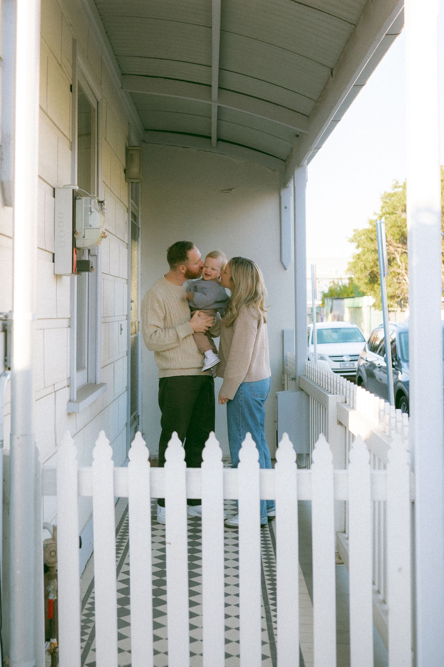 A cozy family photoshoot moment on a covered porch behind a white picket fence in Richmond.
