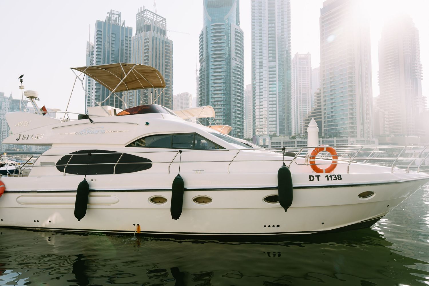 Luxury yacht with UAE cityscape, featuring Dubai Marina's modern skyscrapers and waterfront views in the background.