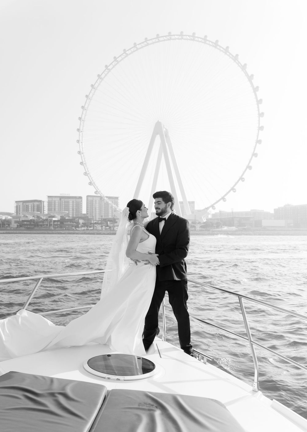 A couple shares a romantic moment on a boat with the Singapore skyline and Singapore Flyer in the background.