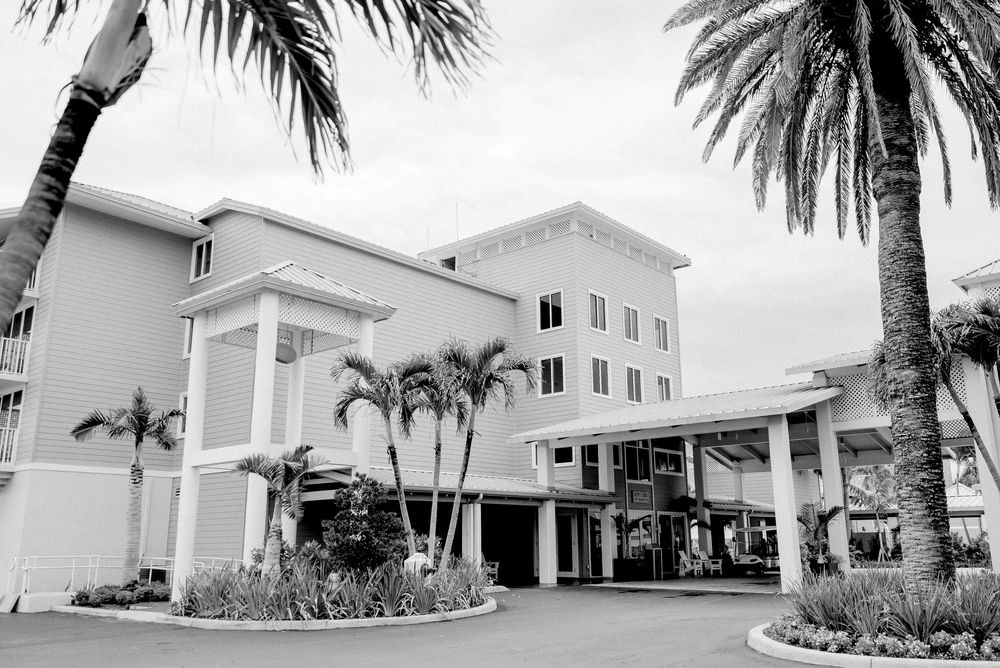 A black and white panoramic view of a luxury beachfront resort with palm trees and modern architecture.