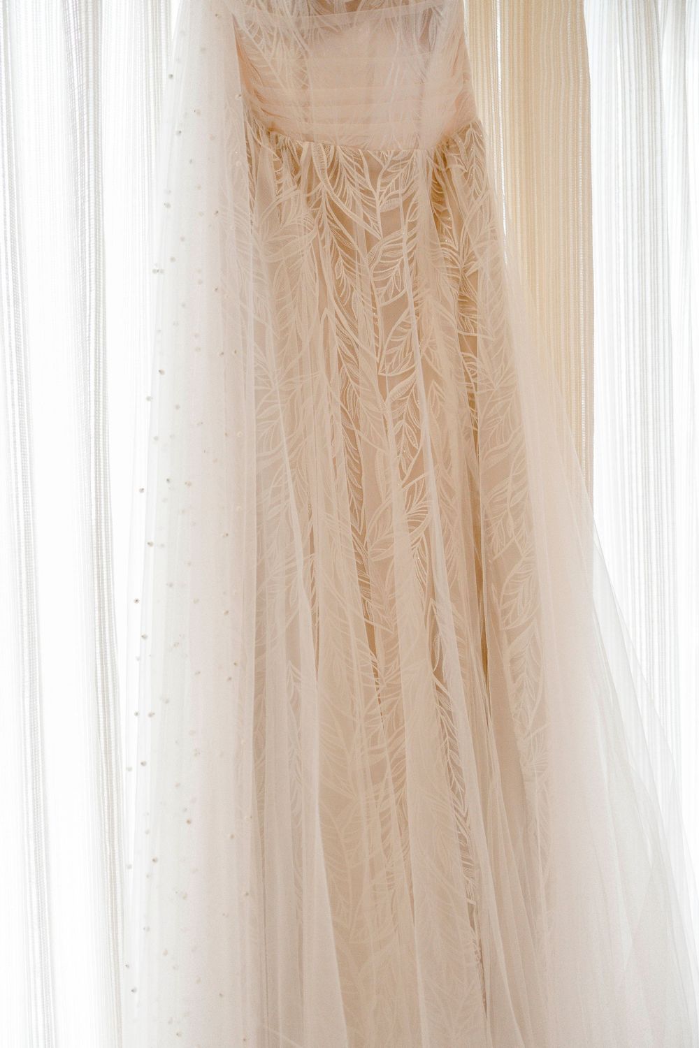 A collection of elegant white and ivory wedding dresses hanging on display in a bridal boutique showroom.