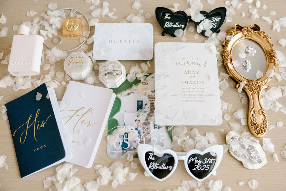Elegant wedding invitations and accessories laid out in a flat lay with navy blue and gold color scheme on a light surface.