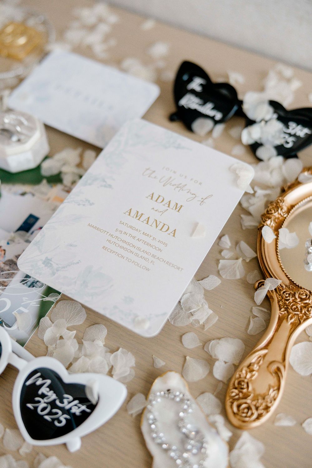 Wedding invitation cards and decorative elements laid out with pearls and gold accents on a neutral surface.