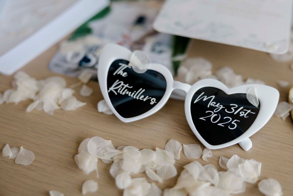 Heart-shaped white sunglasses with black chalkboard centers display the text Resolution and 2024 on a wooden surface.
