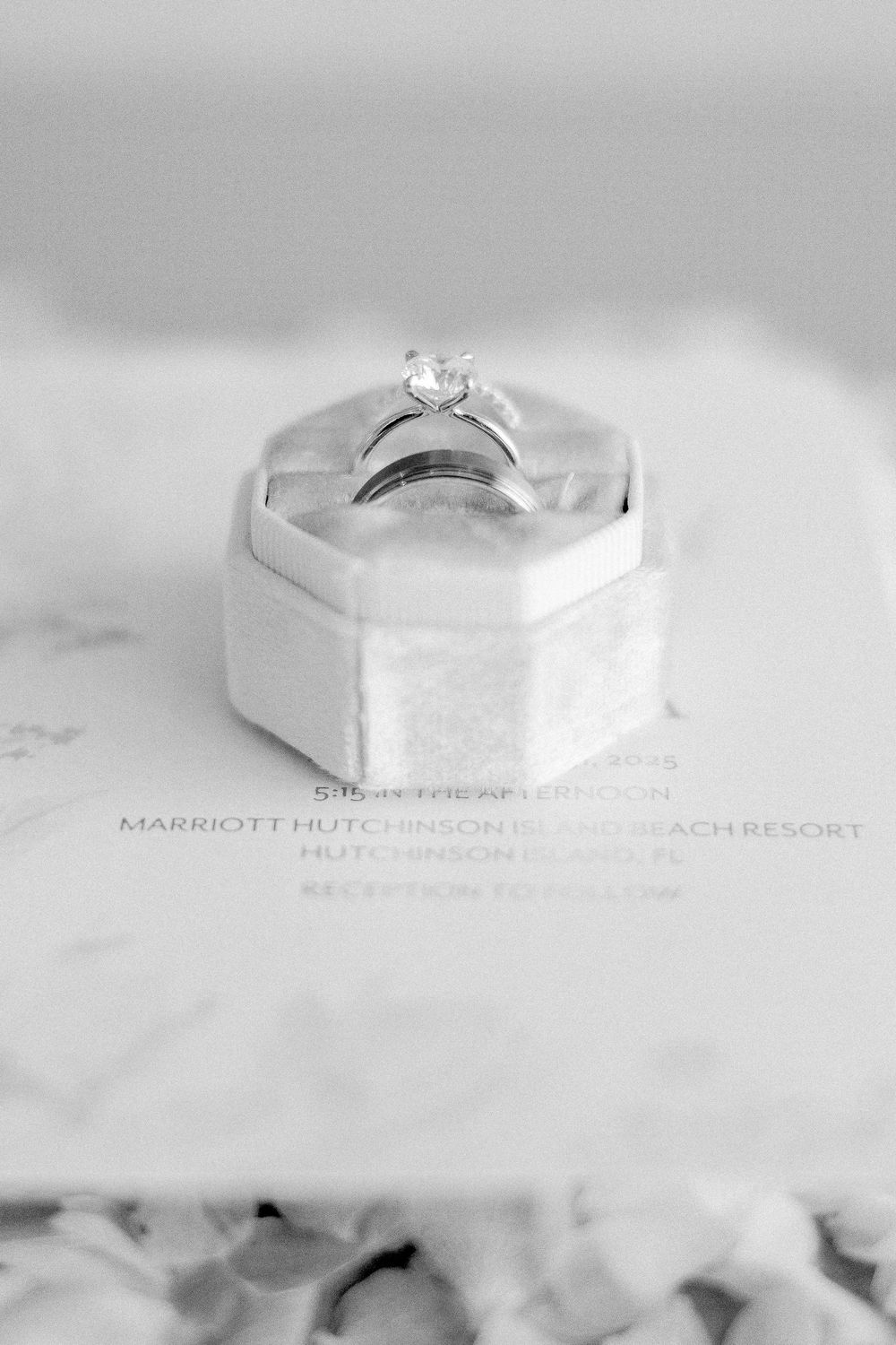 Elegant diamond engagement ring rests in white hexagonal ring box with soft lighting and matte background.
