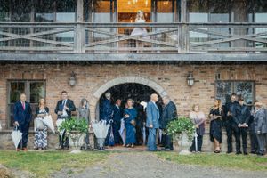 A group gathers outside a rustic brick venue with an arched entrance and wooden balcony during an event.