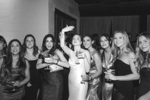 Black and white photo of a celebratory party scene with people holding drinks and posing together.