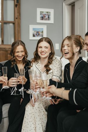 A group of friends laugh joyfully while toasting with champagne glasses at a celebration.
