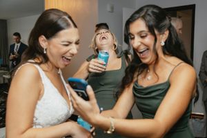 A group of wedding guests share a joyful moment laughing together at a reception celebration.