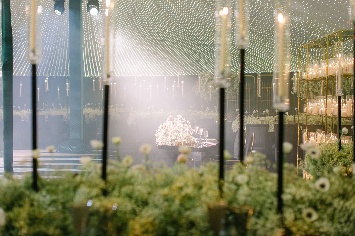 A dreamy outdoor garden setting with string lights and candles creating a romantic atmosphere through a soft-focus lens.