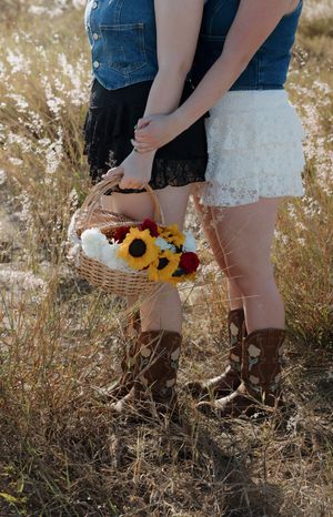 Close-up of boots and sunflowers in a rustic field setting.