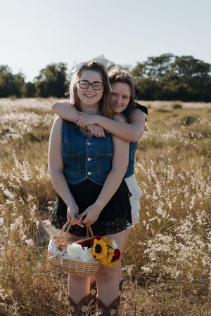 Friends enjoying a sunny day in a meadow with sunflowers and a picnic basket.