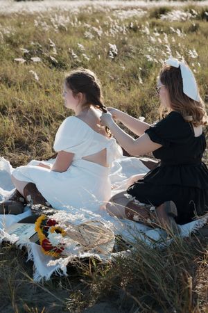 Friends lounging on a white blanket in a meadow with sunflowers and wildflowers.