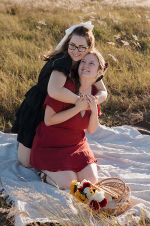 Couple enjoying a picnic together on a white blanket in a sunlit meadow.