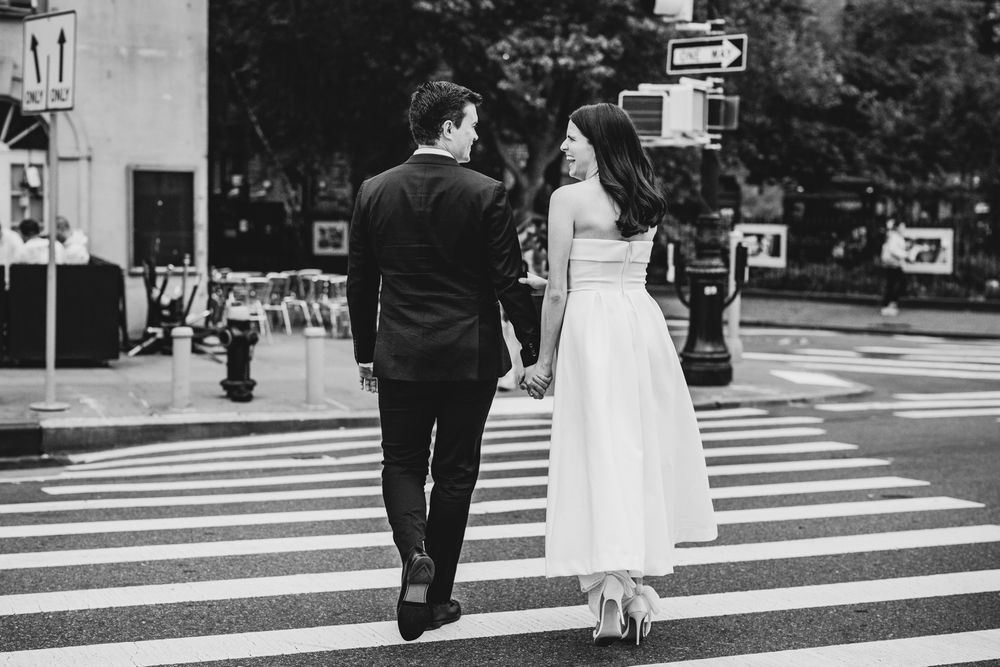 Couple crosses city crosswalk together in black and white photography.