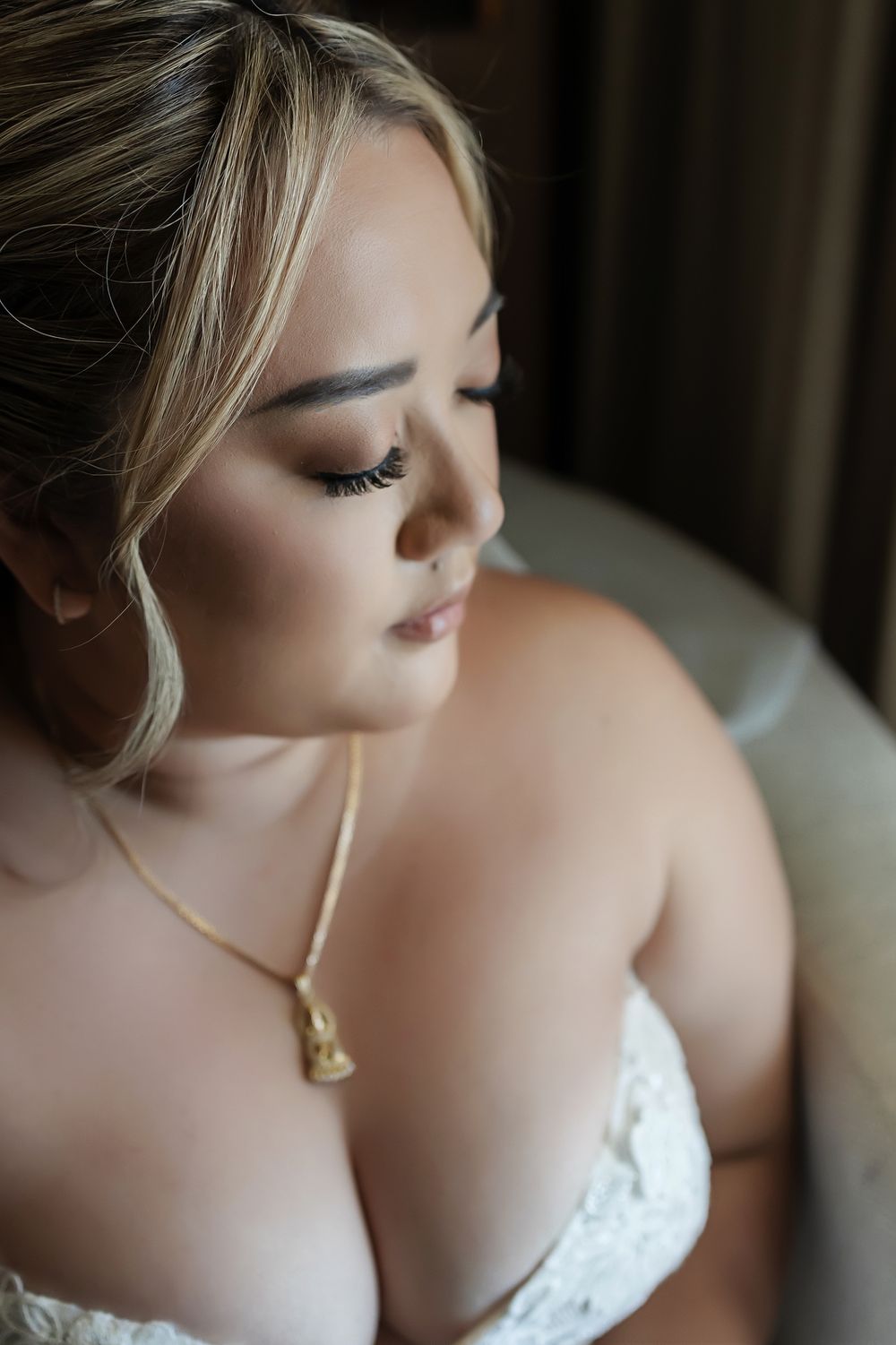 Close-up profile view of a bride wearing white lace with soft makeup and a delicate gold necklace in natural light at Hyatt Ziva Cancun.