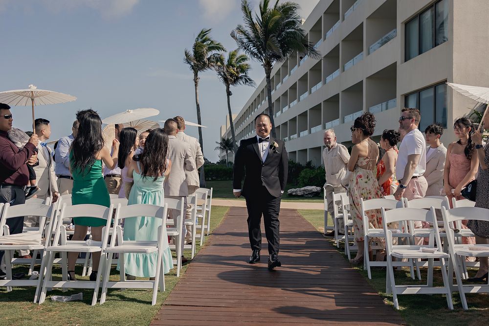 Beachfront wedding ceremony setup with white chairs and palm trees overlooking the ocean.