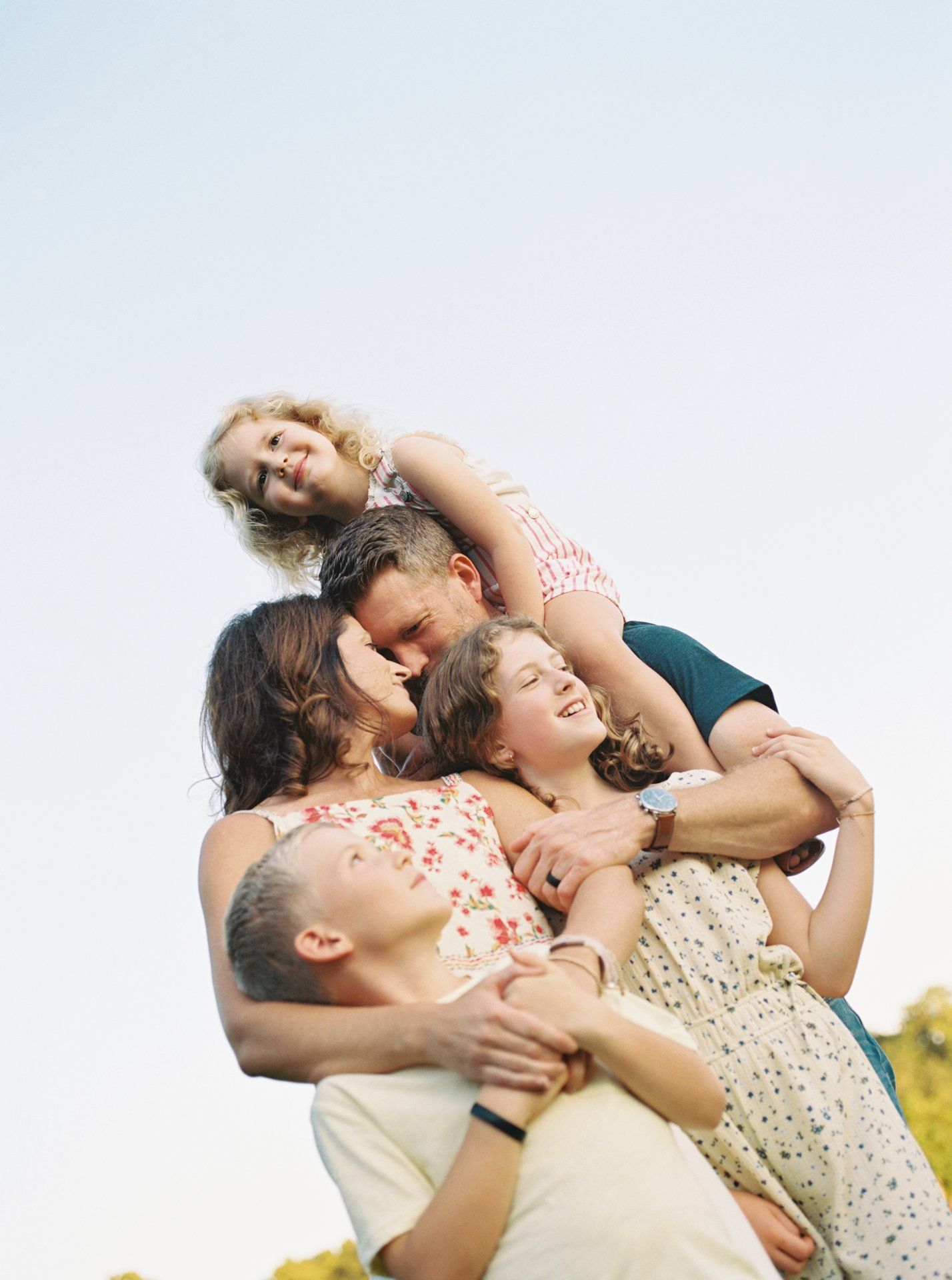 A couple shares joyful laughter while embracing outdoors in warm sunlight.