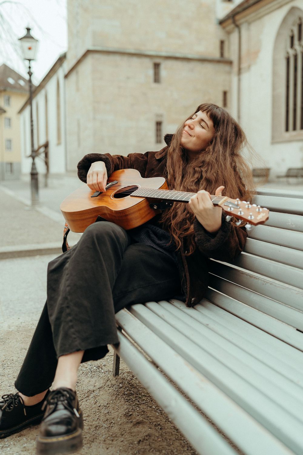 Personal branding an lifestyle photography: Young female musician sitting on a bench in Winterthur playing the guitar.