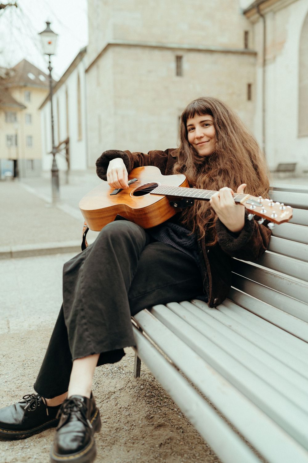 Personal branding an lifestyle photography: Young female musician sitting on a bench in Winterthur playing the guitar.