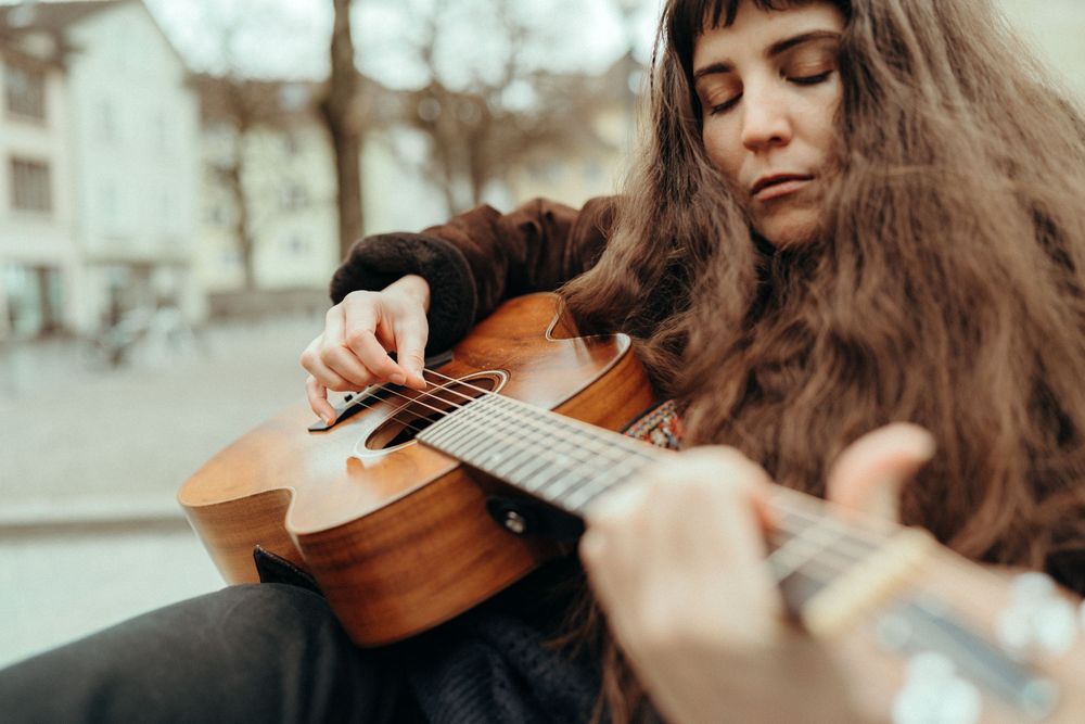 Personal branding an lifestyle photography: Young female musician sitting on a bench in Winterthur playing the guitar.