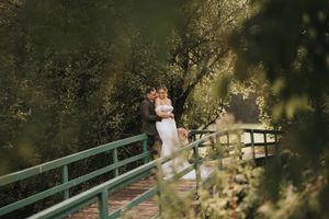 A couple walks across a scenic garden bridge during a romantic outdoor photo session.