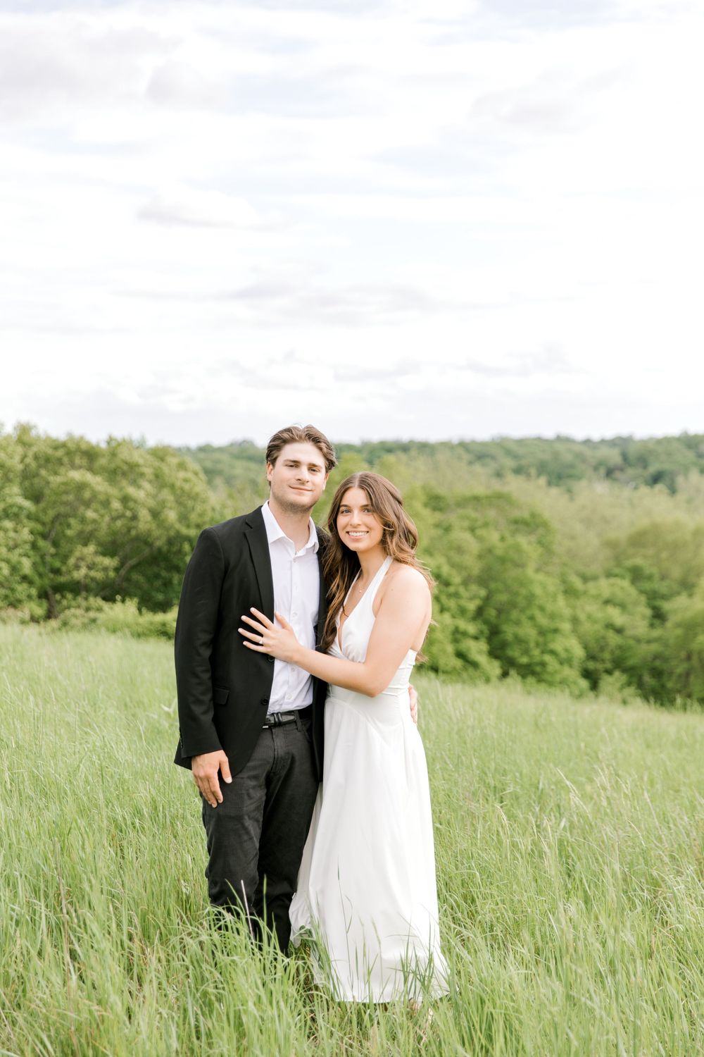 Engaged couple walking hand-in-hand through the tall grass at Natirar Park in Peapack, NJ.