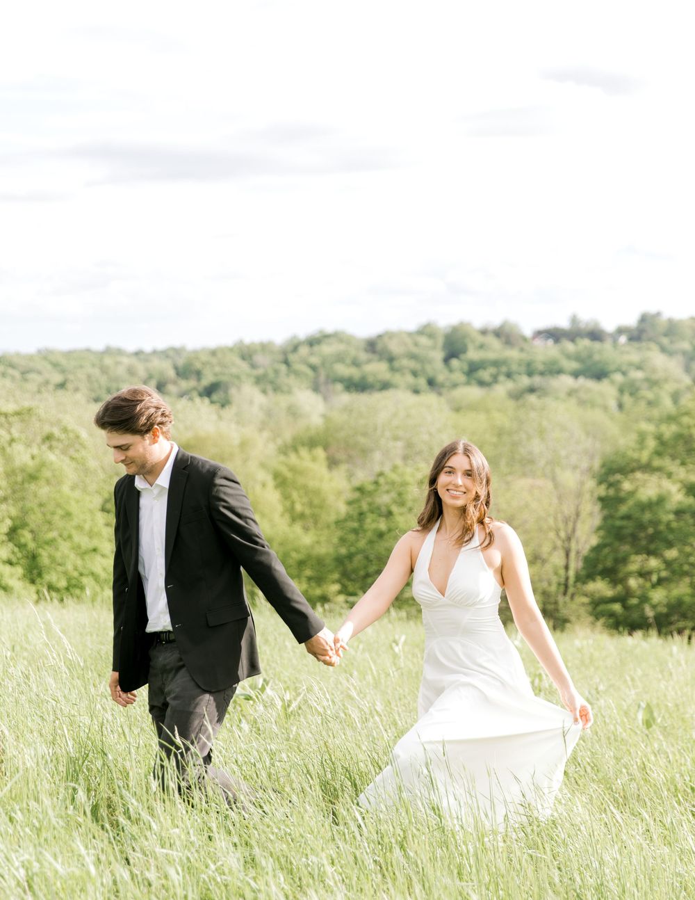 Engaged couple walking hand-in-hand through the tall grass at Natirar Park in Peapack, NJ.