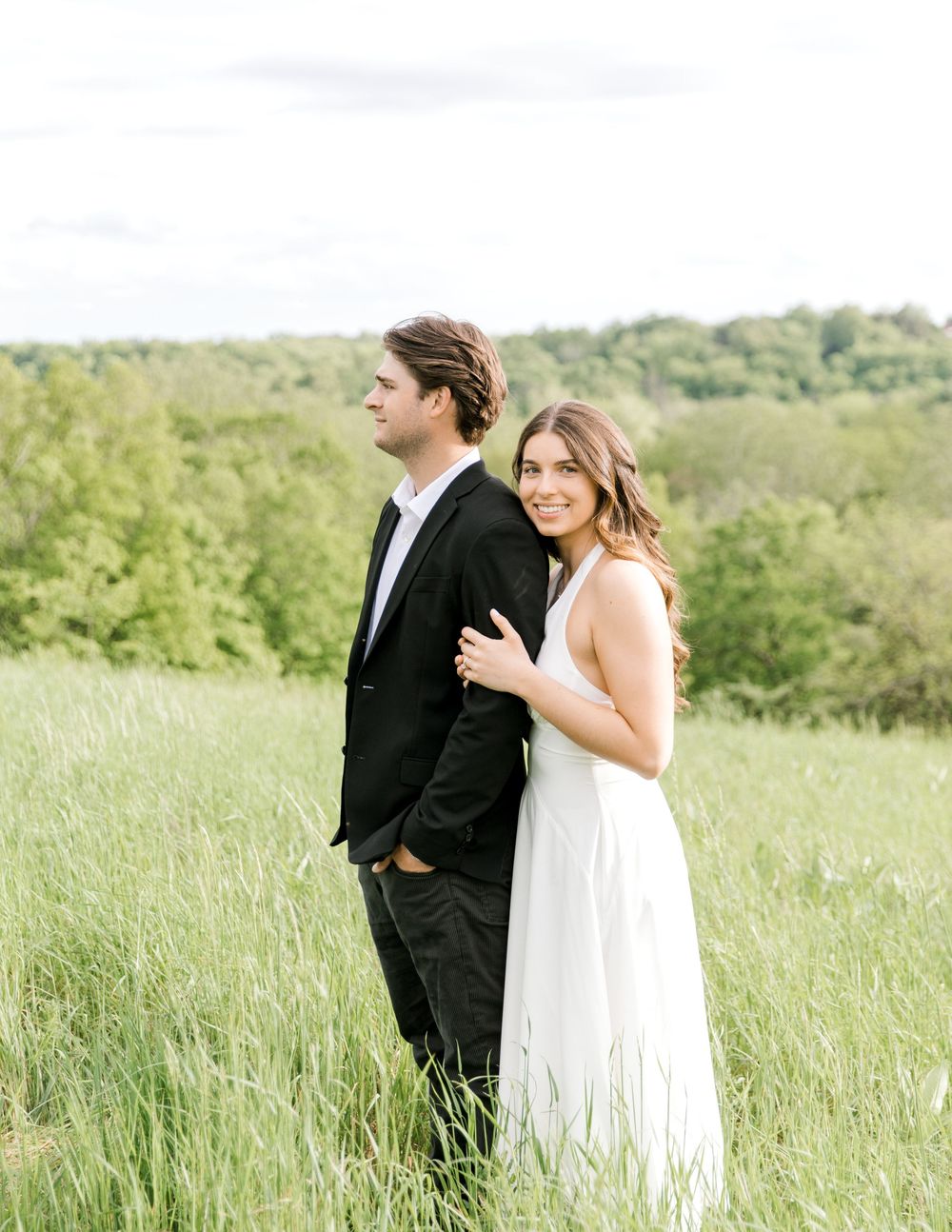 Engaged couple walking hand-in-hand through the tall grass at Natirar Park in Peapack, NJ.