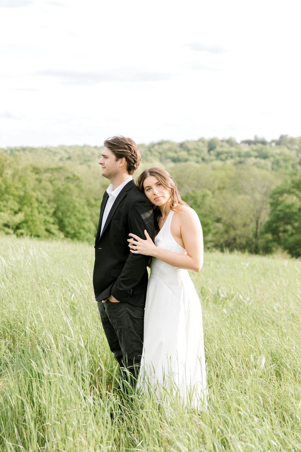 Engaged couple walking hand-in-hand through the tall grass at Natirar Park in Peapack, NJ.
