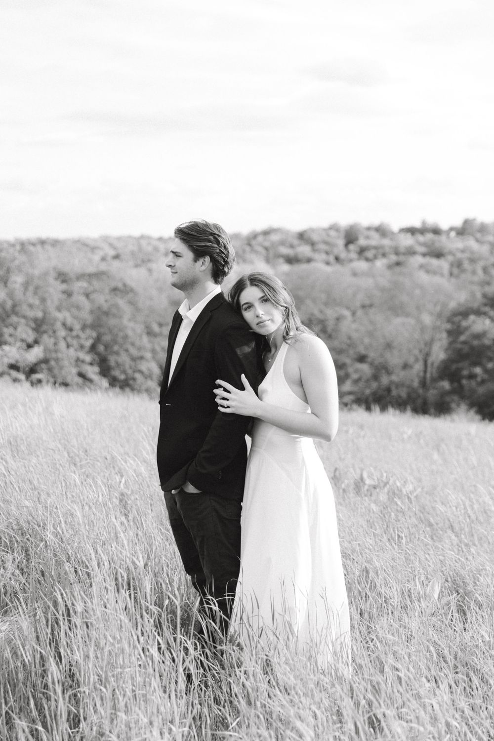 Engaged couple walking hand-in-hand through the tall grass at Natirar Park in Peapack, NJ.