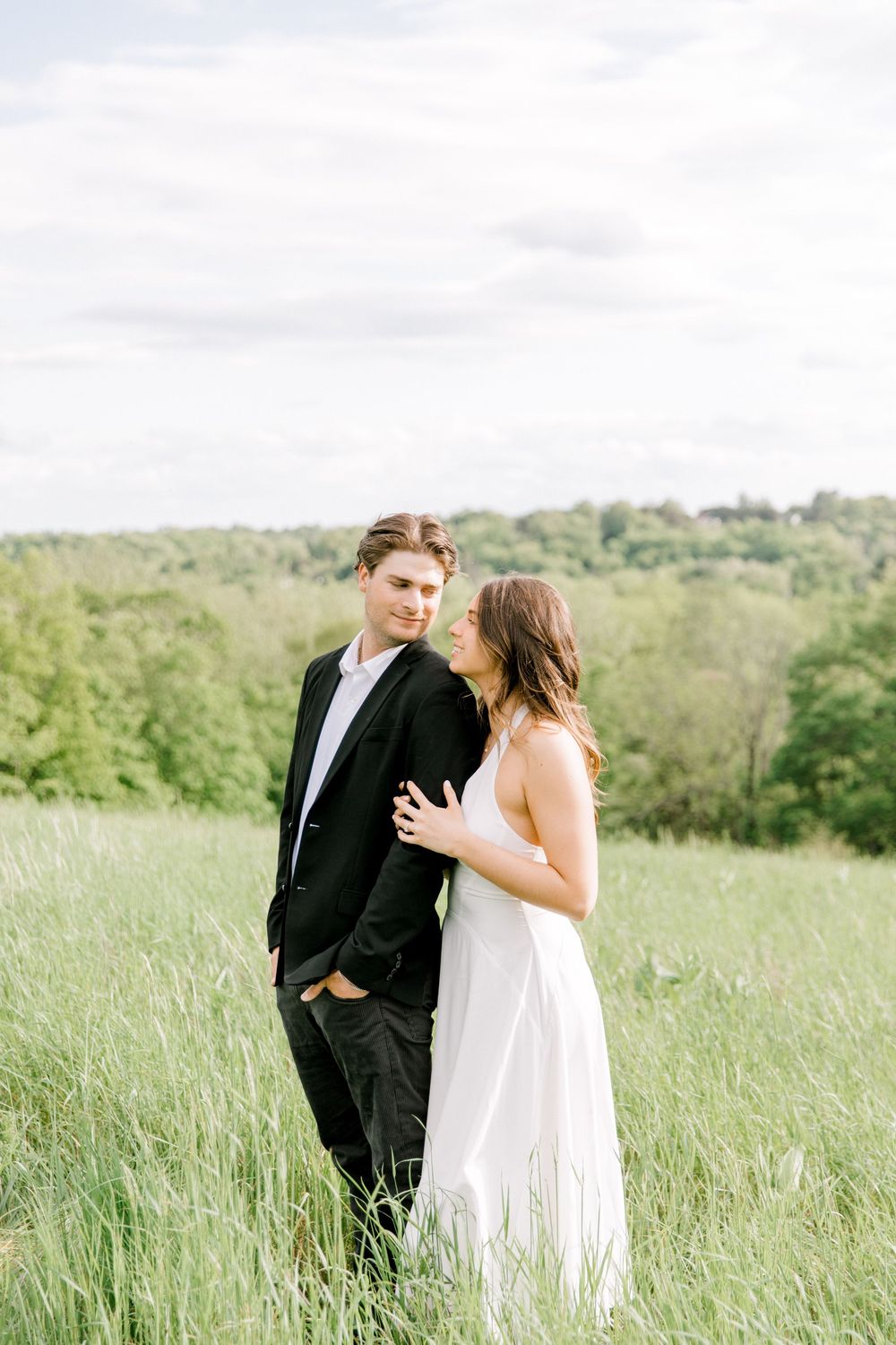 Engaged couple walking hand-in-hand through the tall grass at Natirar Park in Peapack, NJ.